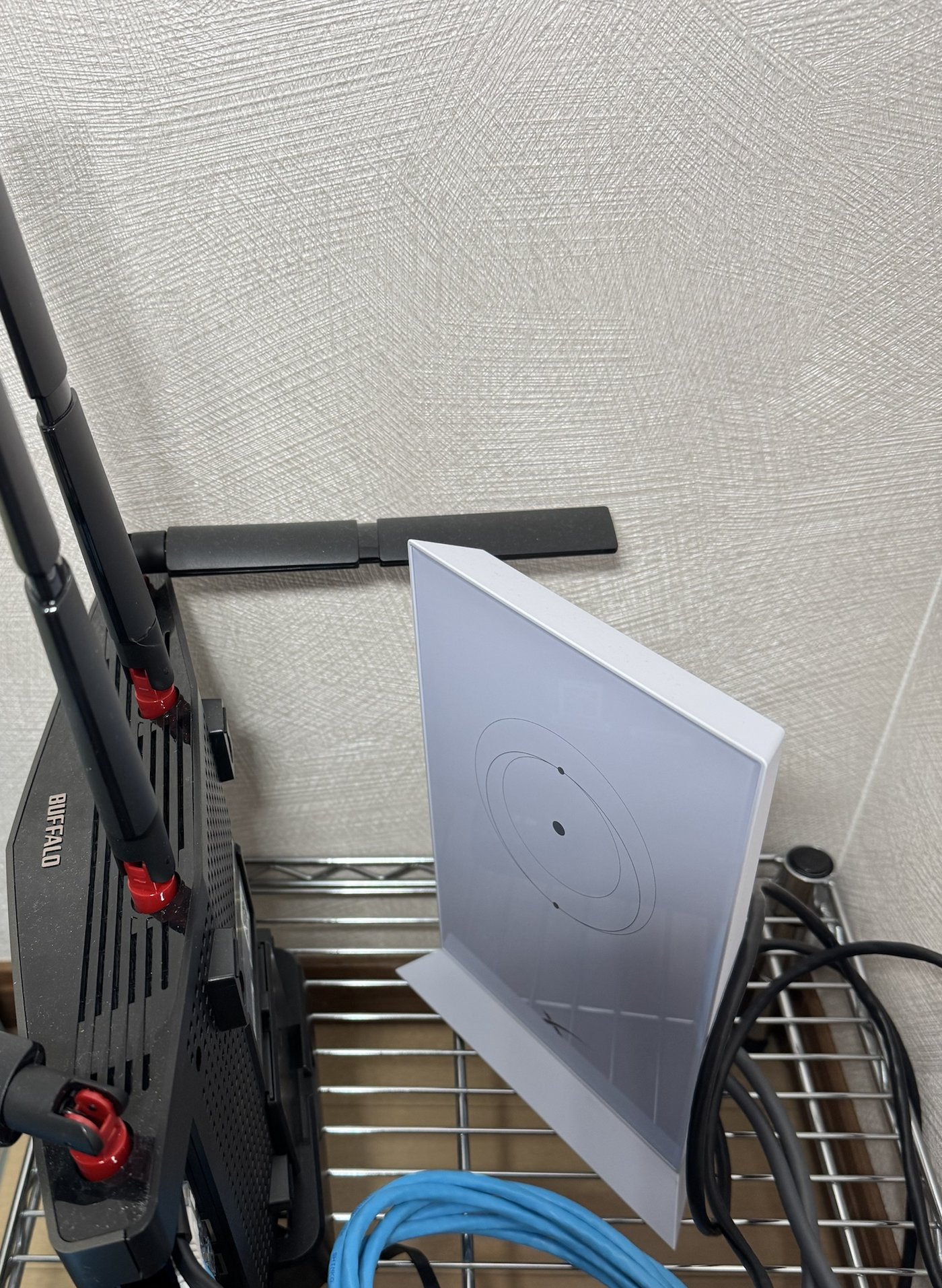 階段下の集約場所。白い平たいのがStarlinkの純正ルーター、左の黒いのがバッファロー WXR-6000AX12S/N